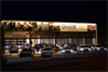 Das Foto zeigt den Firmenstandort von Automobile Gierer; Aufnahme bei Nacht, das Gebäude ist beleuchtet, davor stehen 5 Autos mit ebenfalls beleuchteten Scheinwerfern