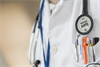 Symbolbild für Arzt - zu sehen ist ein Ausschnitt eines Arzt-Oberkörpers im weißen Kittel mit  Stethoskop mit
