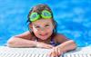 Bild zeigt ein kleines Mädchen mit Schwimmbrille am Beckenrand