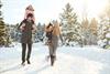 junge Paar wandert mit zwei Kindern und Schlitten durch die tief verschneite Winterlandschaft